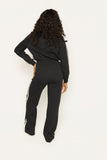 Tall woman wearing a black track jumpsuit, back view